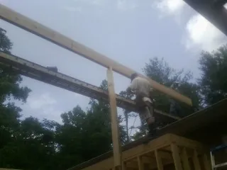 Carpenter setting a ridge beam over a new addition frame — Ice Dam Removal by Roofing Brothers in George