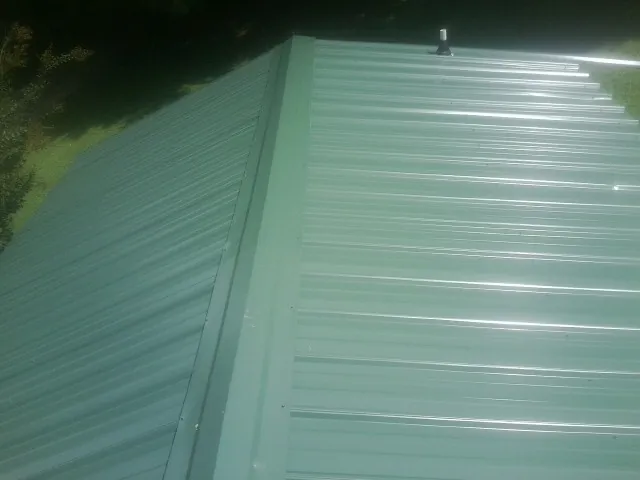 New green metal panels meeting at the ridge of a roof — Flat Roof Repair work by our crew in George