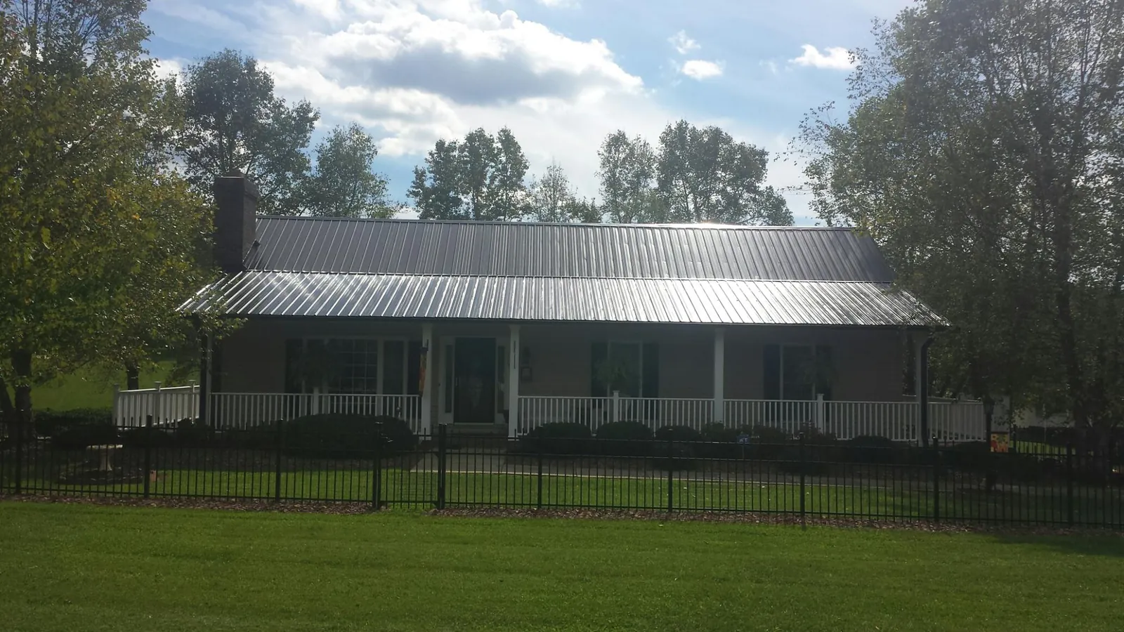 Gray metal roof on a brick ranch with a full width front porch — Gutter Guard Installation work by our crew in George