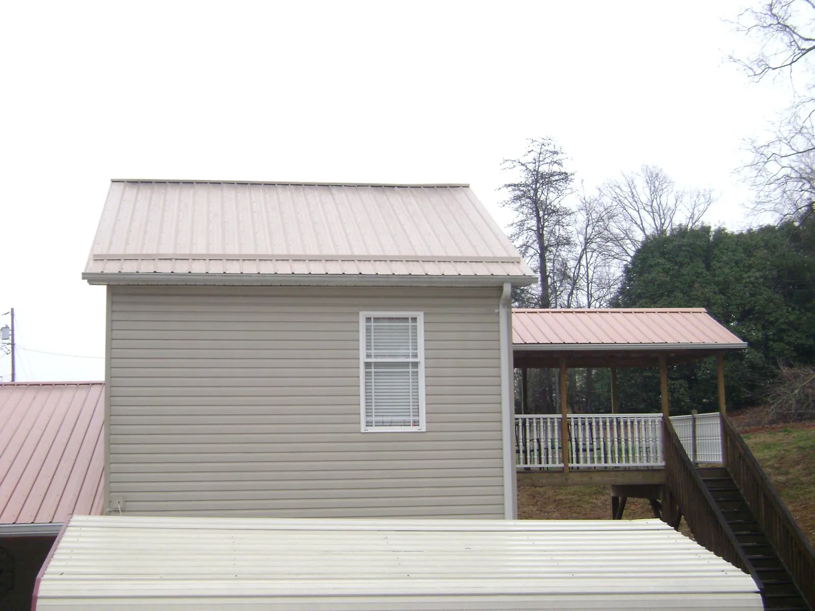 Tan metal roofs on a two story addition and attached porch, from a Roof Replacement job in George